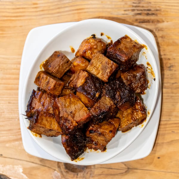 A white bowl filled with glistening, dark brown cubes of David Alan Alan's Smokehouse & Saloon's BBQ brisket burnt ends.