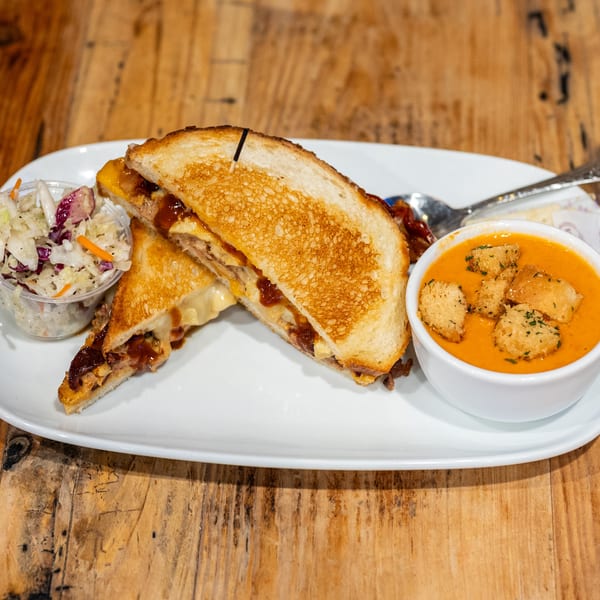 BBQ grilled cheese sandwich with coleslaw and a side of tomato soup with croutons.